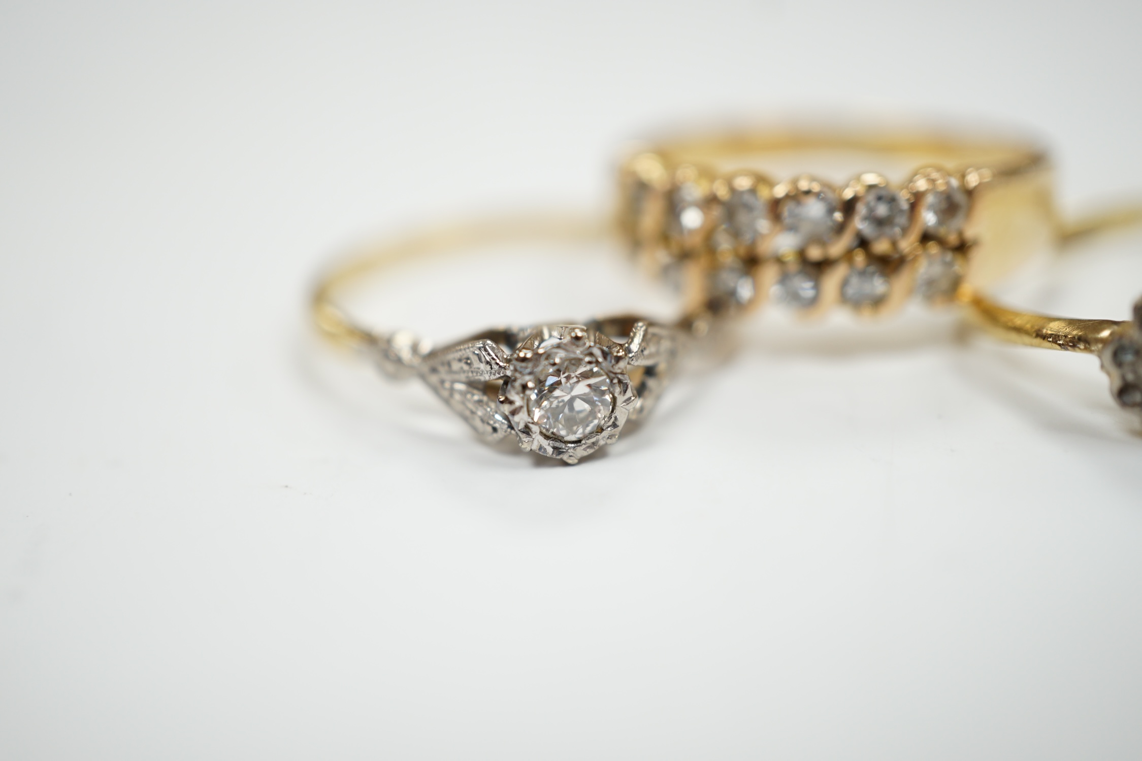 Three assorted yellow metal and gem set rings including an 18ct, plat and illusion set solitaire diamond ring, size Q, gross weight 8.1 grams.